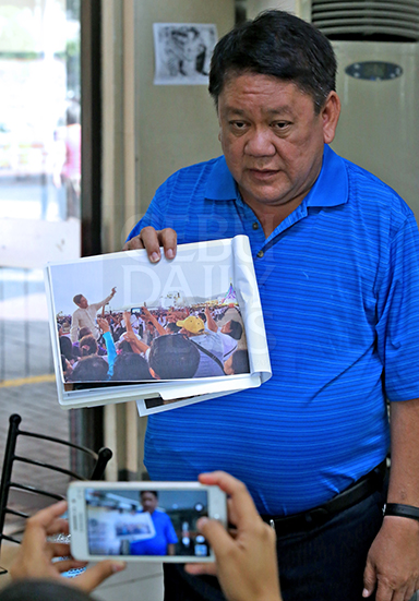 Former Cebu City mayor Tomas Osmena shows a photo of suspended Cebu City Mayor Michael Rama taking a selfie during the Statio Orbis Mass at the South Road Properties. (CDN PHOTO/JUNJIE MENDOZA)