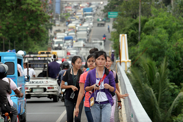 Pedestrians, including workers and students, choose to walk across the old Mandaue-Mactan Bridge than ride a PUJ because of the traffic congestion caused by the bridge repairs. (CDN PHOTO/JUNJIE MENDOZA)