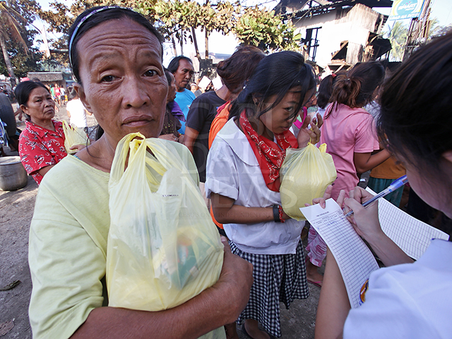 The fire victims of Sitio Alliance of Two Hearts, Barangay Basak, Mandaue City receive relief goods donated by the office of the 6th district Rep. Luigi Quisumbing. (CDN PHOTO/JUNJIE MENDOZA)