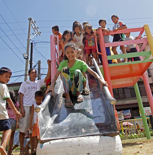 Pasil children have a grand time trying out the slides in the newly opened playground. (CDN PHOTO/LITO TECSON)