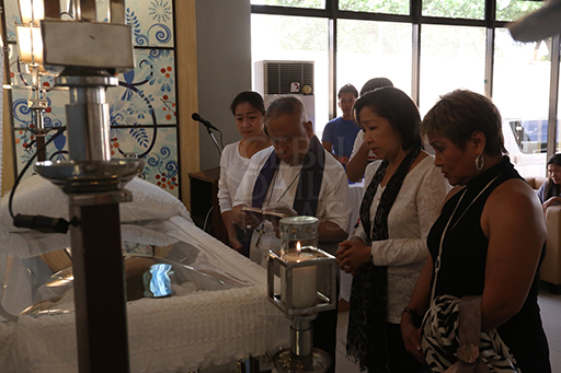 Retired Bishop Antonio Ranola blesses the body of the late Provincial Board member Thadeo "Teddy" Ouano. With Bishop Ranola are Thadeo's wife Glenda (2nd from right, front row), daughter Mandaue City Councilor Lollipop Ouano (left), son Jonkie Ouano (back to Ranola in white polo shirt) and their relatives at St. Peter's Chapel in Mandaue City. (CDN PHOTO/JUNJIE MENDOZA)