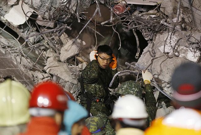An army soldier tries to detect signs of life in the rubble of a  collapsed building in Tainan, Taiwan. (AP PHOTO)