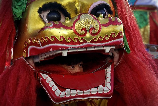 A lion dance performer looks out from the mouth of the lion head at Ditan Park to mark the first day of Chinese Lunar New Year in Beijing. (AP PHOTO)