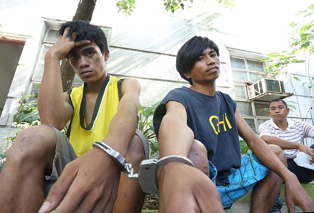 Elmo Relativo (left) and Raymond Albuera, suspects in the killing of a 15-year-old student in Argao town, wait outside the Cebu Provincial Prosecutor’s office during the filing of the murder case against them. (CDN PHOTO/JUNJIE MENDOZA)