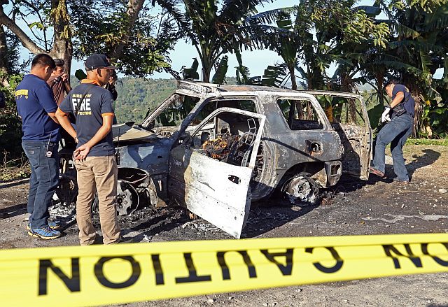 Police and fire personnel check on the car that burst into flames in Lower Busay. (CDN PHOTO/LITO TECSON)