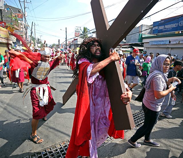 An actor playing the role of a Roman soldier whips Jesus Christ, played by Raffy Anor, as he carries the wooden cross along the streets of Cebu City during the Buhing Kalbaryo/ (CDN PHOTO/LITO TECSON)