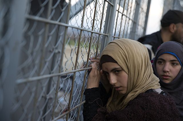 A young Syrian woman leans on the metal fence separating them from Macedonia, at the Greek border station of Idomeni, Sunday, Feb. 28, 2016. More than 5500 refugees and migrants are stuck in the Greek-Macedonian borders (AP Photo/Petros Giannakouris)