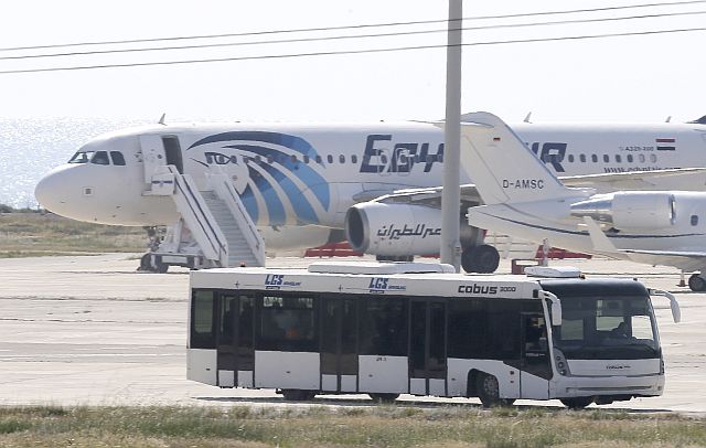 A bus carrying some passengers from the hijacked EgyptAir aircraft drives by the plane at Larnaca Airport in Cyprus. (AP)