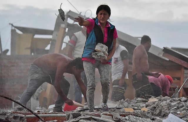 A woman in Ecuador removes rocks as she searches for her missing husband, who is believed to be buried under the rubble. (AFP)