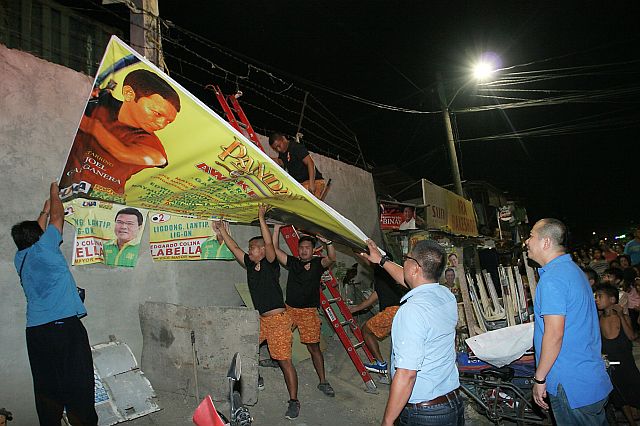 Regional Comelec director Jose Nick Mendros (center) and Cebu City Comelec officer Marcel Sarno (right) lead the removal of illegally sized and placed election posters and tarpaulins. (CDN PHOTO/JUNJIE MENDOZA)