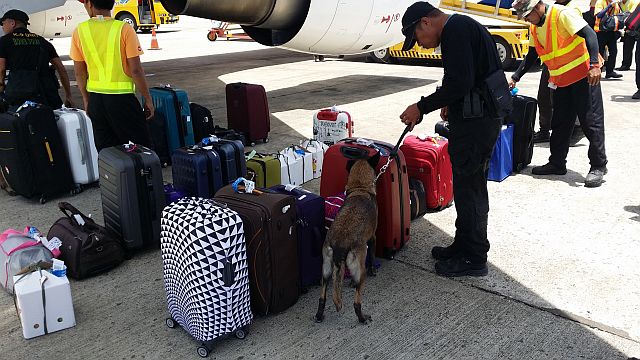 The K9 unit and other security personnel inspect the luggage after the public assistance office of the Mactan Airport received a bomb threat which turned out to be a hoax. (CDN PHOTO/NORMAN MENDOZA)