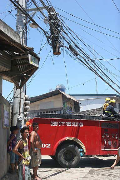 SILOY IS WATCHING: A fire truck passes to a cut utility post hanging at Laray street barangay San Roque Talisay City. Did this cuase danger to the passing pedestrians and motorist? ATTENTION: BARANGAY SANROQUE OFFICIALS AND UTILITY FIRMS