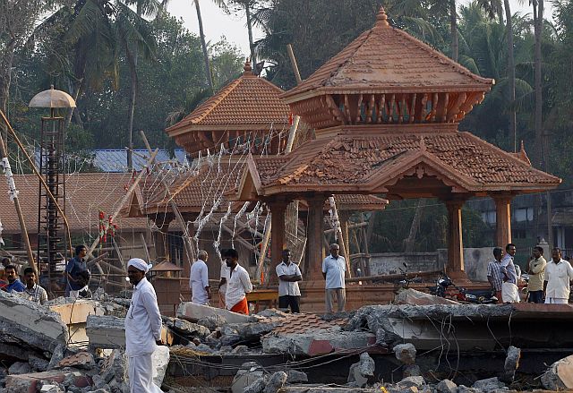 People check out the damaged structures after a massive fire broke out Sunday during a fireworks display at the Puttingal Devi temple complex in India. (AP)