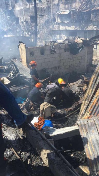 Firefighters retrieve the body of one of the seven killed in the early morning fire in Pahina Central, Cebu City. (CDN PHOTO/IZOBELLE T. PULGO)