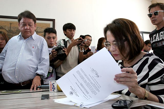 With her husband Cebu City Mayor-elect Tomas Osmeña looking on, Councilor and Acting Mayor Margot Osmeña signs some documents in her office minutes after taking oath. (CDN PHOTO/JUNJIE MENDOZA)