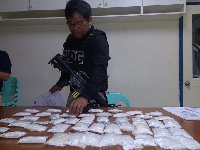 An operative of the Criminal Investigation and Detection Group Central Visayas (CIDG-7) inventories packs of suspected shabu valued at P16 million seized in a raid in Barangay Lamintak Norte, Medellin town Thursday morning. (CDN PHOTO JUNJIE MENDOZA)