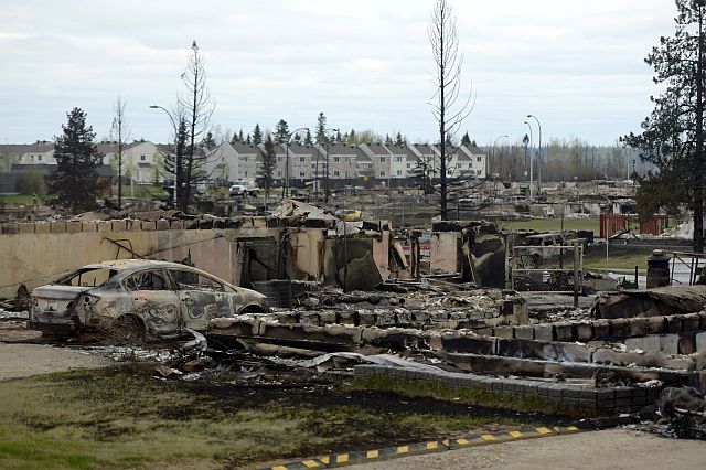 A burned out car and the remains of a house are viewed in the Beacon Hill neighborhood during a media tour of the fire-damaged city of Fort McMurray, Alberta. (AP)