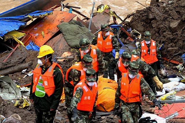 Rescuers carry a body of a victim found at the workers’ dormitory damaged by a landslide in southeast China’s Fujian province. (AP)