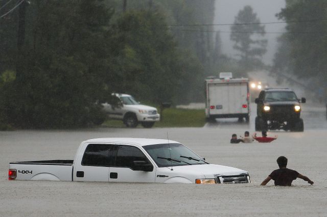 People wade in rising floodwater in Magnolia, Texas. (AP)