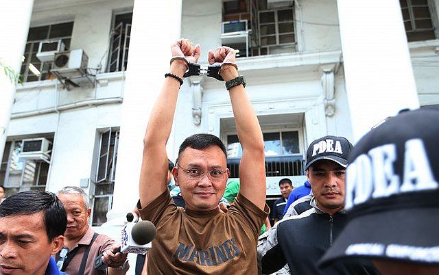 Lt. Col. Ferdinand Marcelino raises his hands as he leaves the DOJ building after attending the preliminary hearing at the office of Senior Deputy State Prosecutor Theodore Villanueva at the Department of Justice in Manila. (Philippine Daily Inquirer File Photo) 
