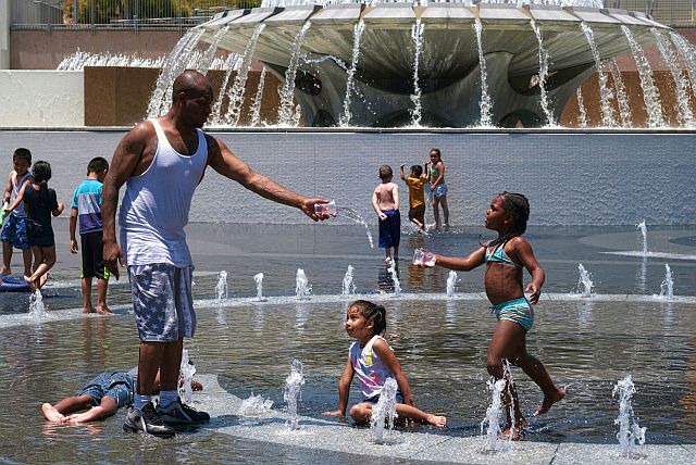 Children cool off from the intense heat in in the Grand Park water fountain in downtown Los Angeles
