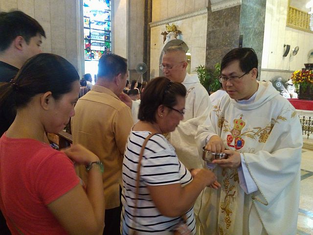 Newly installed rector of Basilica del Sto. Niño offers the Holy Communion to the faithfuls with Archbishop Jose Palma during the mass on Monday morning. (CDN PHOTO/JUNJIE MENDOZA)