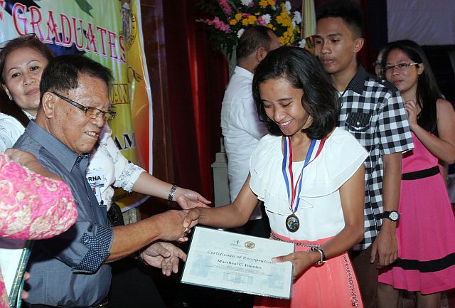 Maeshael Fuentes of Argao town receives a medal and certificate of recognition from outgoing Board Member Julian Daan. Fuentes is one of the 132 scholars of the Provincial Capitol who graduated from college. (CDN PHOTO/JUNJIE MENDOZA)