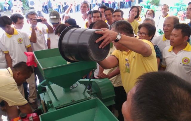 Cebu Gov. Hilario Davide III pours harvested corn into one of the corn mills that the Capitol distributes to farmers. The corn mill costs P120,000 each. (CDN PHOTO/ JOSE SANTINO S. BUNACHITA)