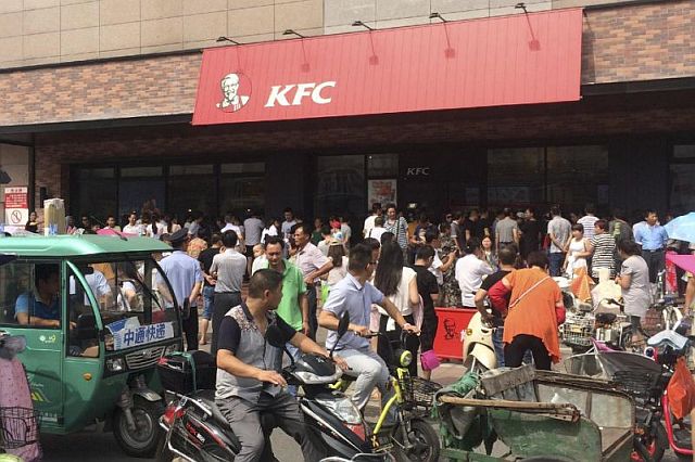 Motorists watch people gather to protest outside a KFC restaurant outlet in Baoying county in east China’s Jiangsu province in this July 19 photo. 