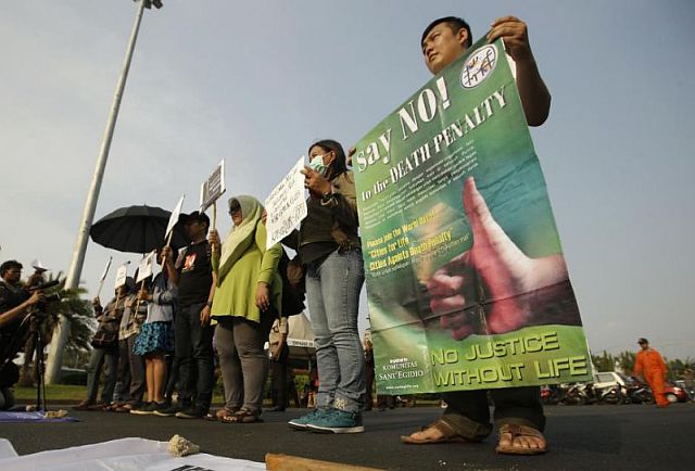 Protesters hold posters as they attend a rally against the death penalty outside the presidential palace in Jakarta, Indonesia on Tuesday. AP