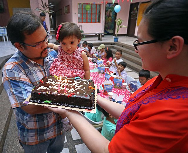 Miguel Osmeña carries his daugther Ana Margarita Victoria who celebrated her 2nd birthday at the Pari-an Drop in Center while her mother, Bea, carries the cake.(CDN PHOTO/LITO TECSON)