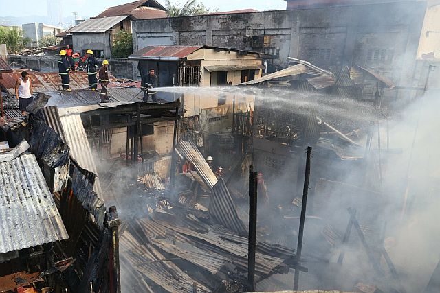 Firemen trail their hose to a burning house in Barangay Tejero. (CDN PHOTO/LITO TECSON)
