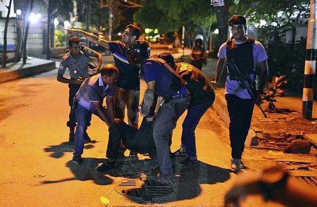 People help an injured person after a group of gunmen attacked a restaurant popular with foreigners in a diplomatic zone of the Bangladeshi capital Dhaka.