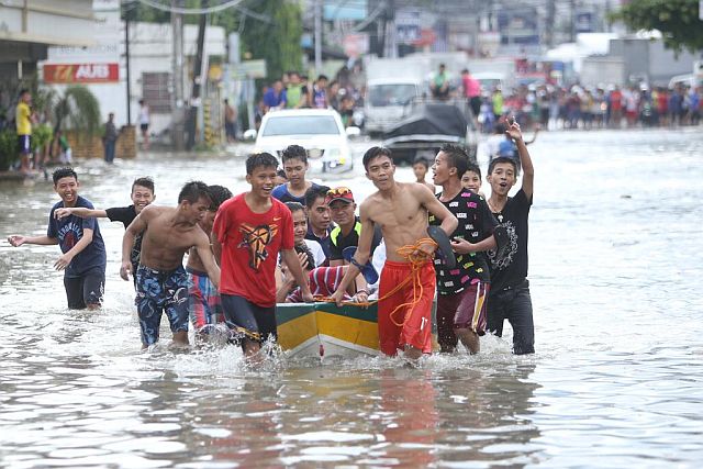 Residents in A.S. Fortuna St., Mandaue City use a boat to ferry stranded people through the flooded area. Pagasa said Cebuanos can expect flooding when rain volume reaches 20 mm level. (CDN PHOTO/LITO TECSON)