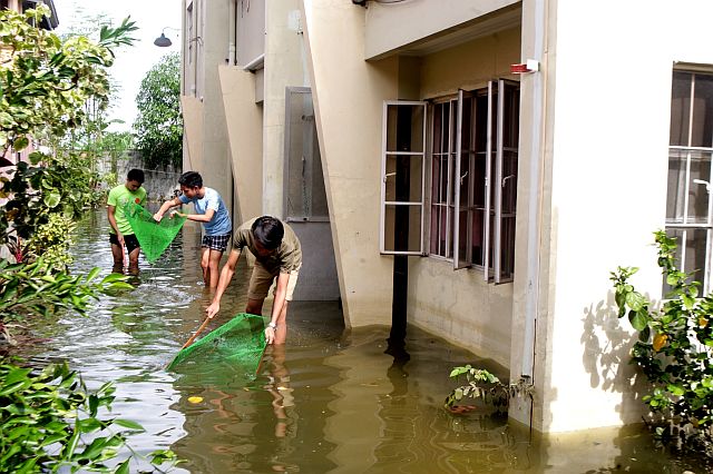FISHING GALORE.  Residents of Sitio B in Barangay  Talamban, Cebu City go  fishing on a flooded street outside an apartment building after a nearby fish pond overflowed on Sunday  following  two days of  heavy rains.  (CDN PHOTO/TONEE DESPOJO)