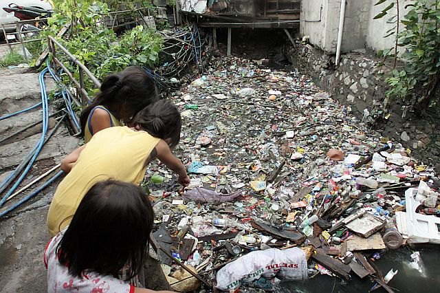Children point to a creek filled with garbage that clogged the waterway at A. Soriano Street in Barangay Carreta.  (CDN PHOTO/JUNJIE MENDOZA)