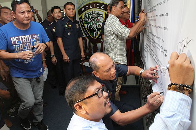 Chief Supt. Noli Taliño, Police Regional Office chief, signs the covenant with Councilor Philip Zafra and barangay officials. (CDN Photo/Junjie Mendoza)
