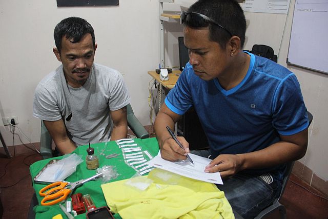 Lapu-lapu City Jail inmate Harney Cinco (in grey shirt), 48, interrogated by JO3 Louie Quiachon for possession of packs of shabu, paraphernalia and repacking materials.