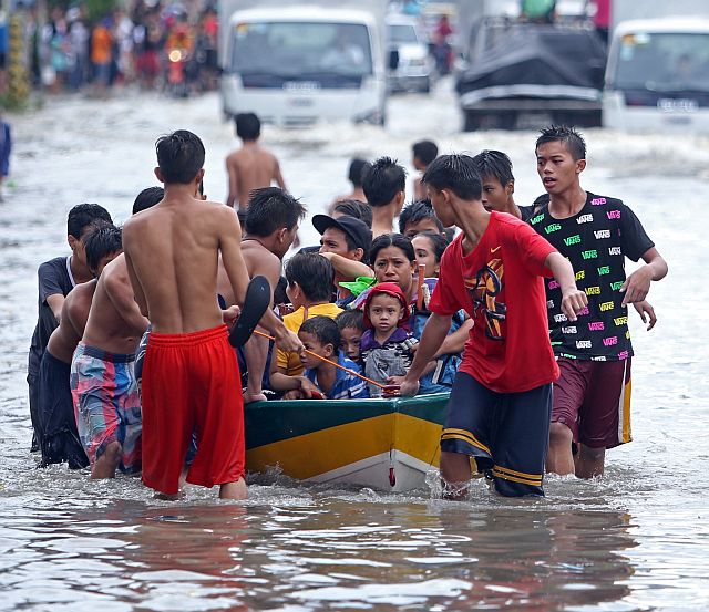  A BOAT RIDE on A.S. Fortuna Street, Mandaue City allows stranded commuters to cross the road that remains knee-deep in water 24 hours after it was submerged in about  5 feet of floodwater on Friday. (CDN PHOTO/LITO TECSON)