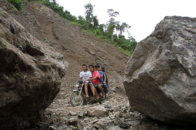 MANIPIS landSLIDE:  A “habal-habal”  (passenger motorcycle) with four persons on board navigates through two huge rocks that tumbled down in a landslide that closed for several hours on Saturday the Manipis Road, which connects Barangay Don Andres Soriano in Toledo City and  Barangay Manipis in Talisay City. (CDN PHOTO/JUNJIE MENDOZA)