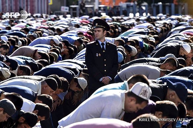 A police officer stands among Russian Muslims praying outside the central mosque in Moscow on July 5 during celebrations of Eid al-Fitr. /AFP