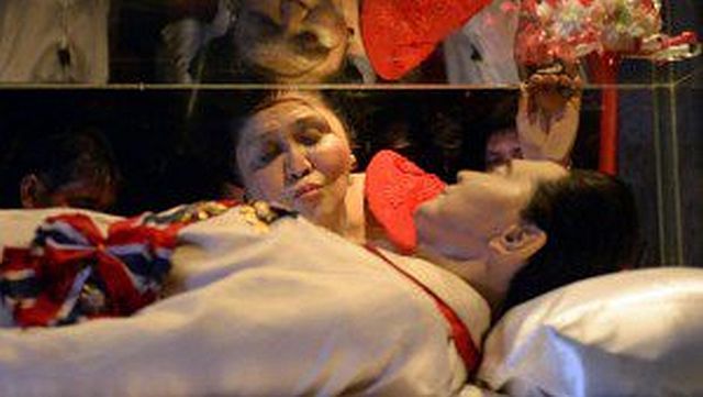 Former first lady Imelda Marcos kisses the glass case that contains the frozen remains of former dictator and president Ferdinand Marcos in this July 2, 2014 photo. /AFP