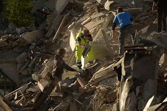 Rescuers and residents clear debris in search for victims in damaged homes after a strong earthquake hit Amatrice, Italy, on Wednesday. (AFP)