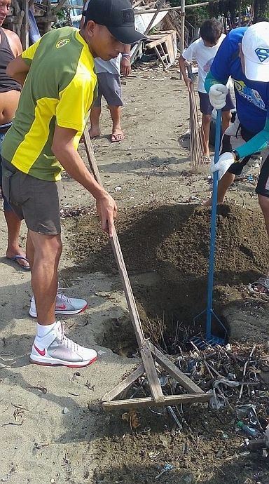 Veco cleanup volunteers bury the biodegradable wastes in a sand pit.  (CDN PHOTO/TITO P. TAN)