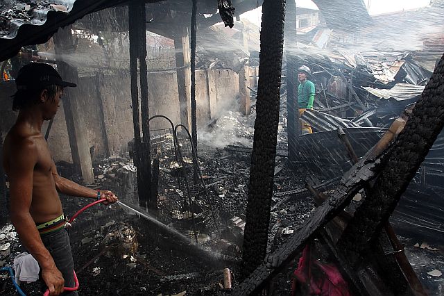 A resident helps put out the fire that occurred in Bamboo Village, Barangay Basak Pardo. (CDN PHOTO/JUNJIE MENDOZA)