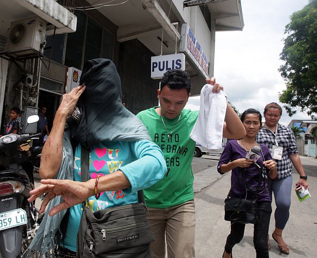 The mother of jailed suspected drug lord Alvaro “Barok” Alvaro covers her face after leaving the Danao City police precinct. She will face a charge of grave threats for supposedly claiming that she can order her son to kill the police that shot down her  son Medz. (CDN PHOTO/TONEE DESPOJO)