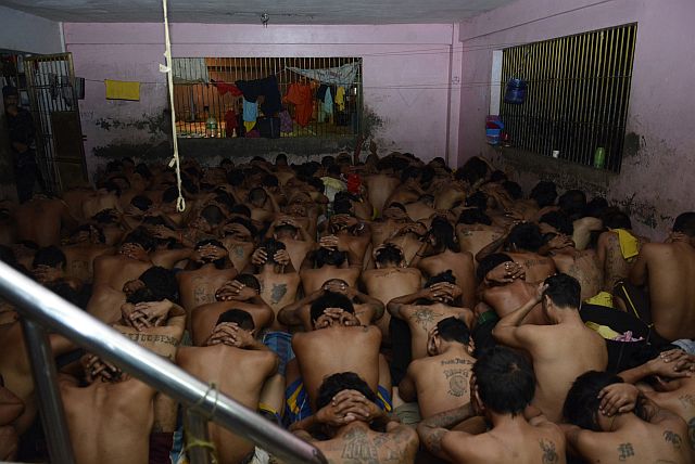 Inmates squat naked while being guarded by a Special Weapons and Tactics (SWAT) team at the male dorm of the Cebu City Jail. (CDN PHOTO/CHRISTIAN MANINGO)