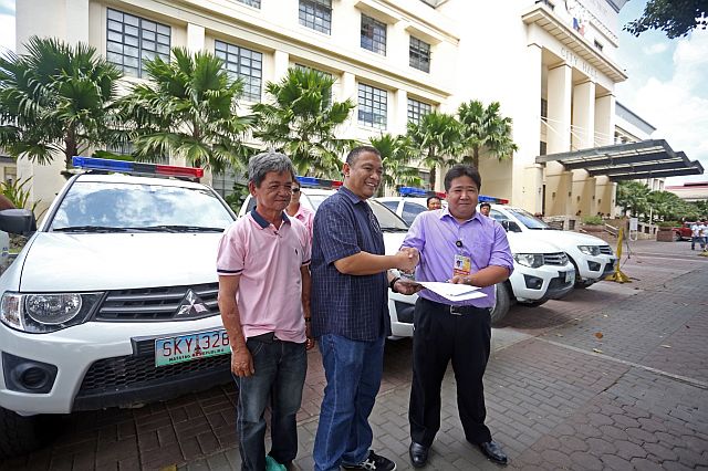 Cebu City public information officer Nagiel Bañacia turns over the patrol vehicles to CCTO head Rafael Yap at the City Hall grounds. (CDN PHOTO/LITO TECSON)
