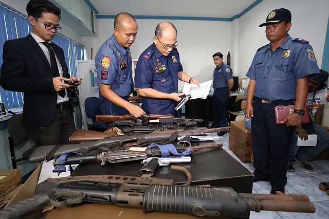 Chief Supt. Noli Taliño (second from right), PRO-7 chief, inspects the firearms turned over by Daanbantayan Mayor Vicente Loot through Chief Insp. Petronio Gracia, Daanbantayan police chief (right), as Loot’s lawyer Russel Soliano Pernites looks on.  (CDN PHOTO/JUNJIE MENDOZA)