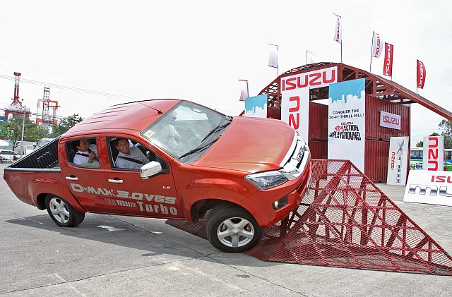 Emmanuel Aligada, president of Isuzu Automotive Dealership Inc. (in front passenger seat)  is joined by Isuzu Cebu Inc. general manager Steve Gingco (in back seat) on board a 3.0-liter D-Max pickup during the Isuzu 4x4 Action Playground Cebu at the SM City Cebu open parking lot. (CDN PHOTO/JUNJIE MENDOZA)